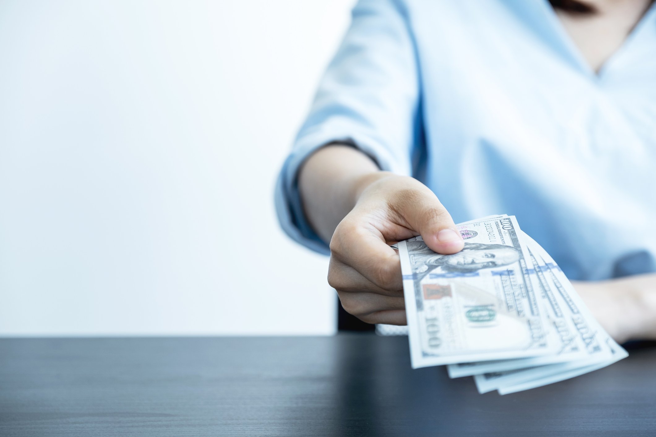Person handing over dollar bills.