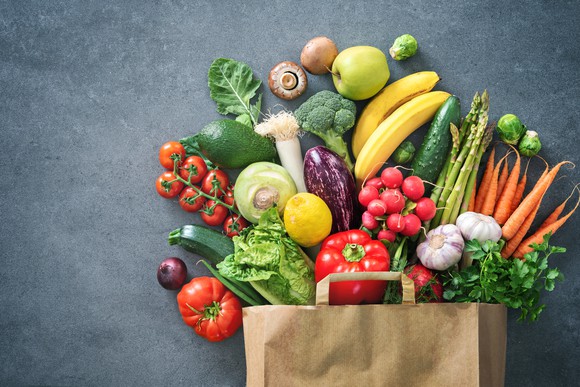 A paper grocery bag filled with fresh fruit and vegetables.