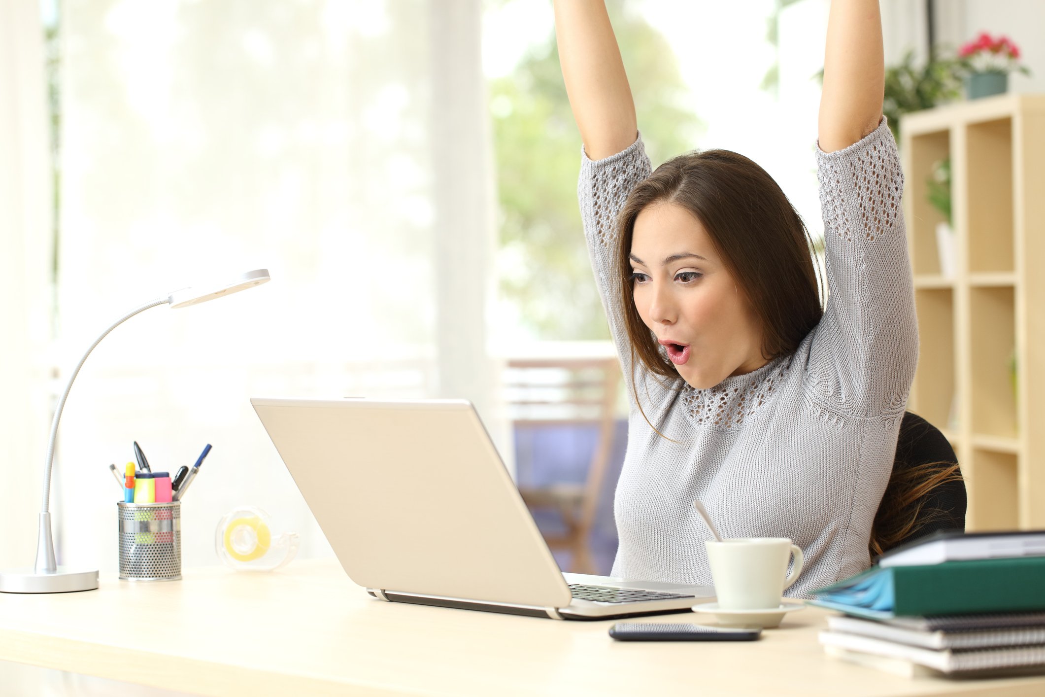 Woman cheering in front of laptop