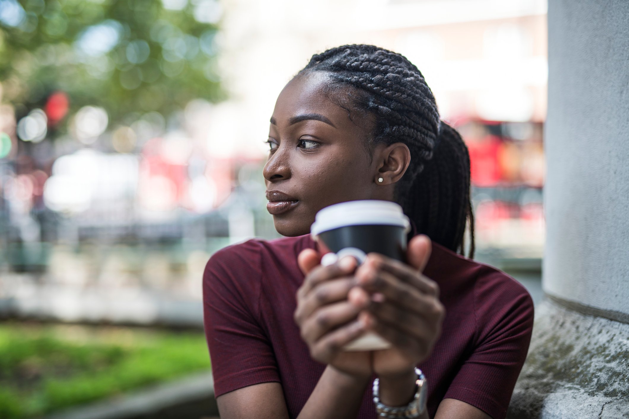 A young woman holding a to-go coffee cup.