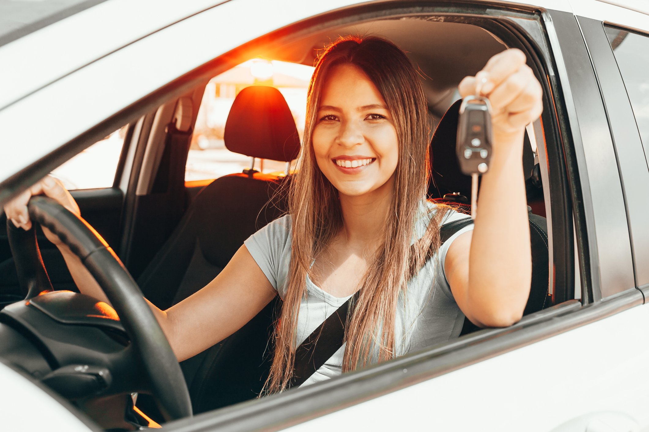 happy new car buyer behind wheel showing off key fob