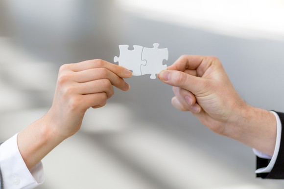 Two hands holding connected jigsaw puzzle pieces