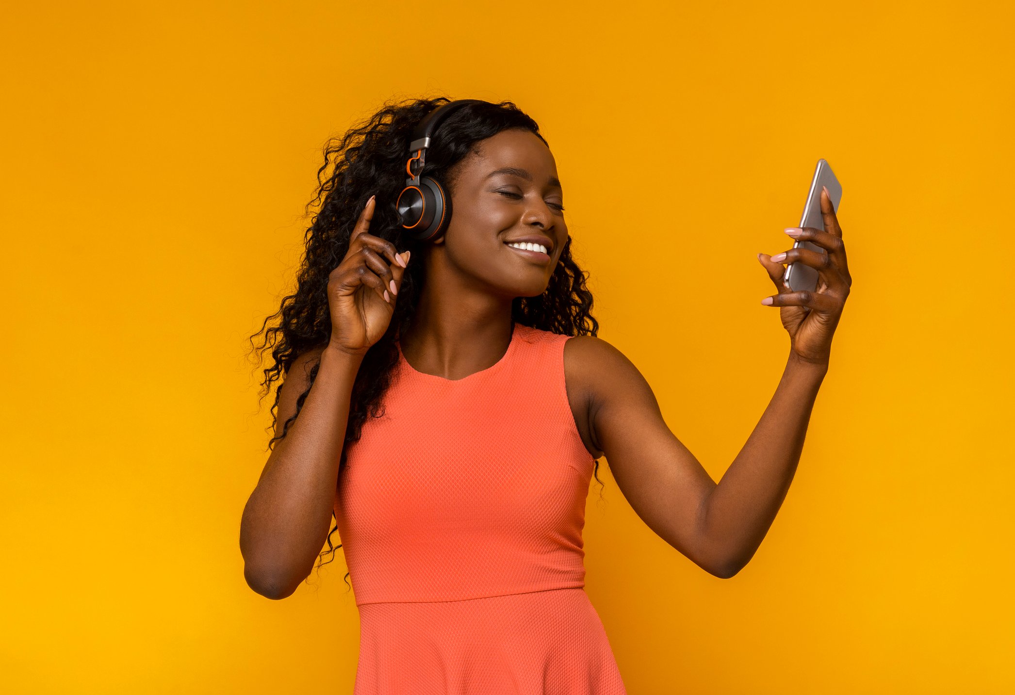 A young woman listens to music on her smartphone.