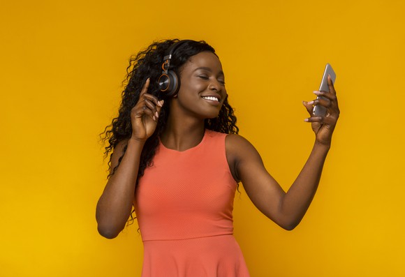 A young woman listens to music on her smartphone.
