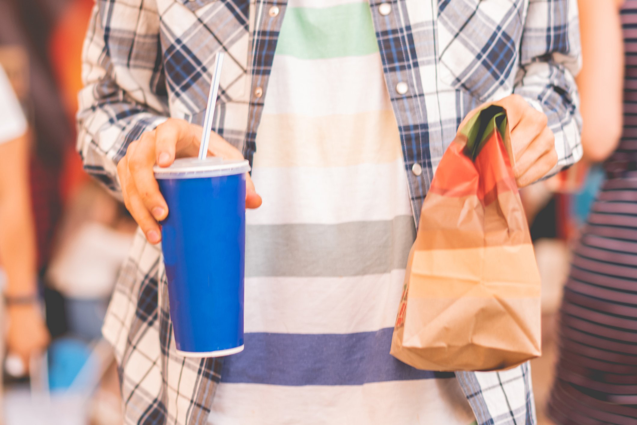 A man holding a bag of to-go food and a soda.