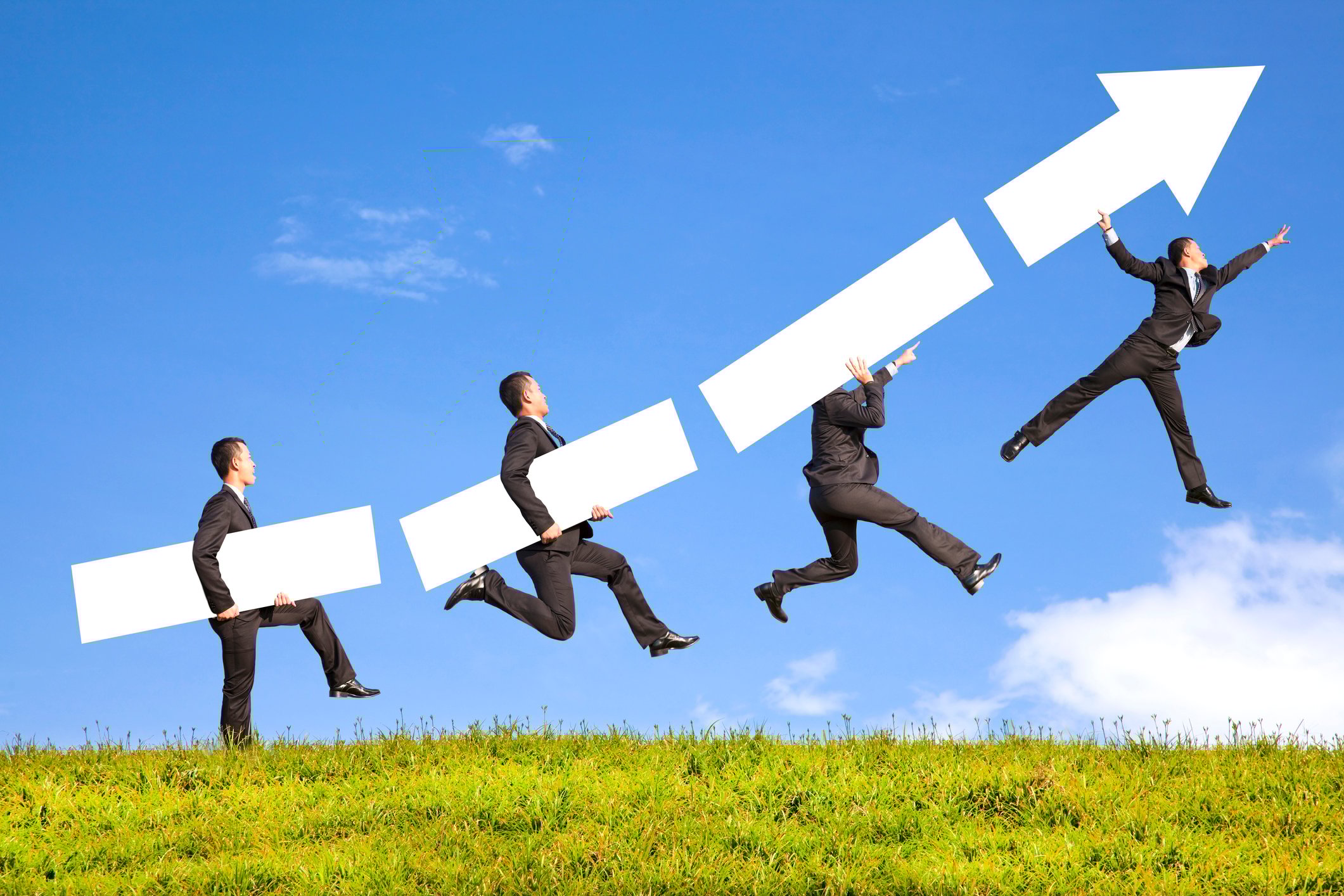 Four businessmen are carried progressively higher by pieces of a rising arrow.