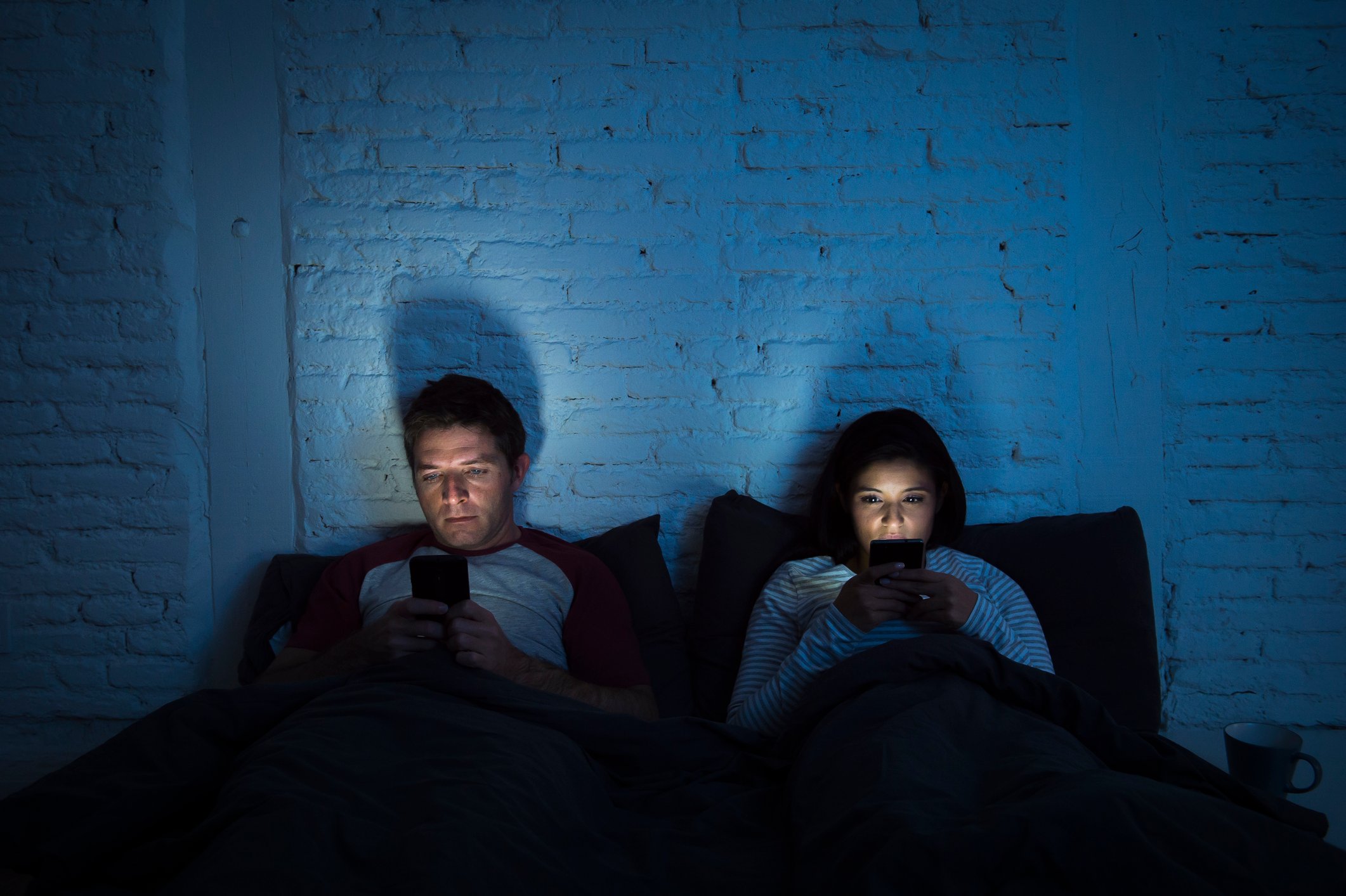 Couple in bed using smartphones