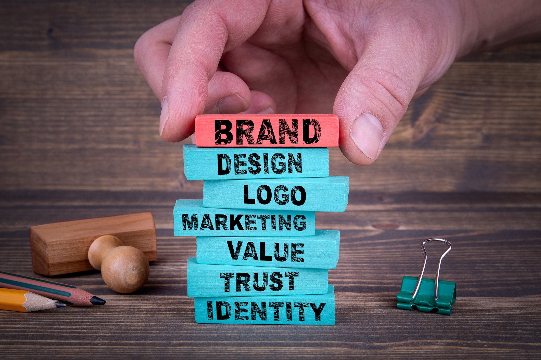 The words brand, design, logo, marketing, value, trust, and identity are printed on stacked blocks.