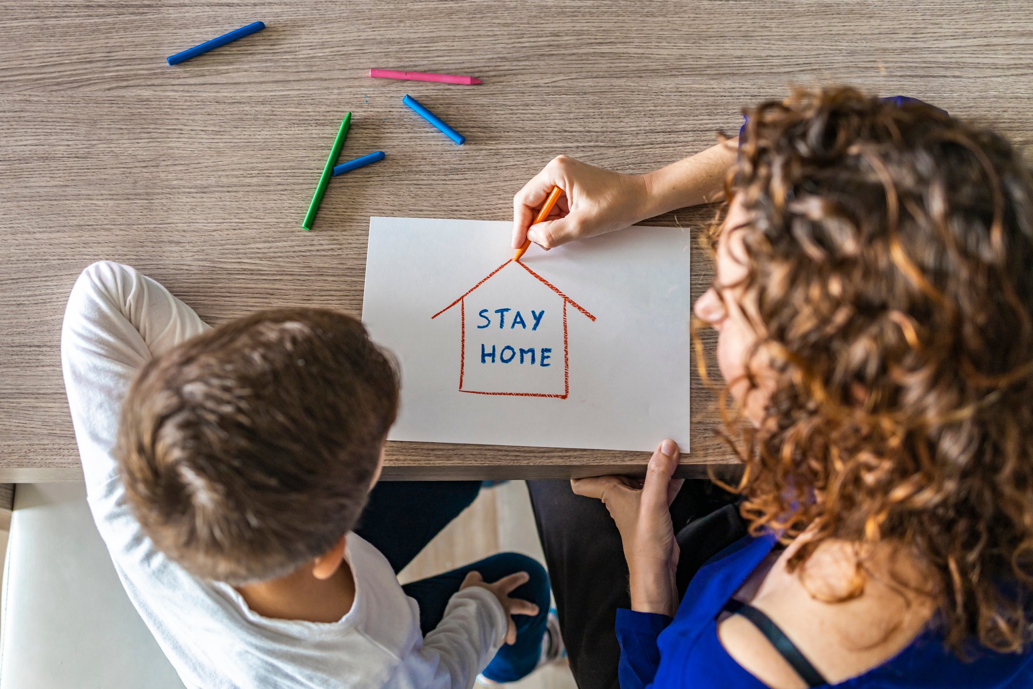 A woman and child illustrate a house enclosing the words "stay home".