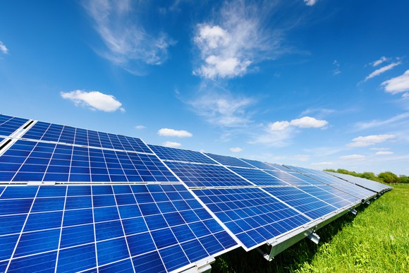 Solar panels in a green field with a bright blue sky. 