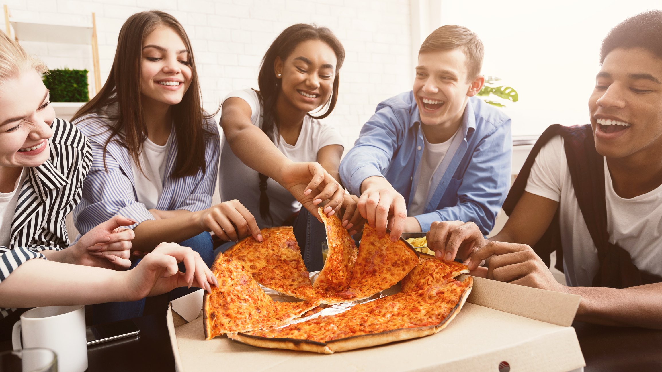 Five young adults share a pizza.