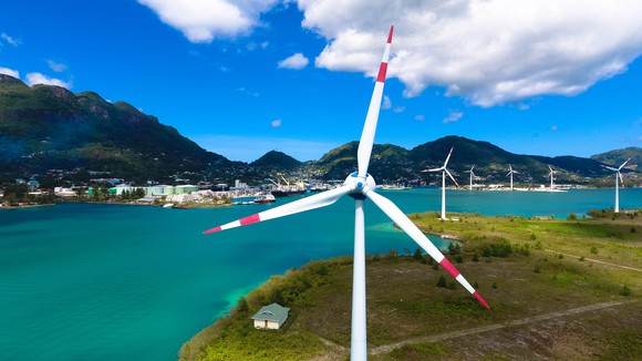 A windmill farm next to a body of water.