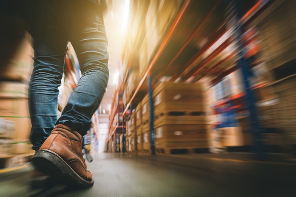 Shopper walking down the aisle of a retail warehouse.