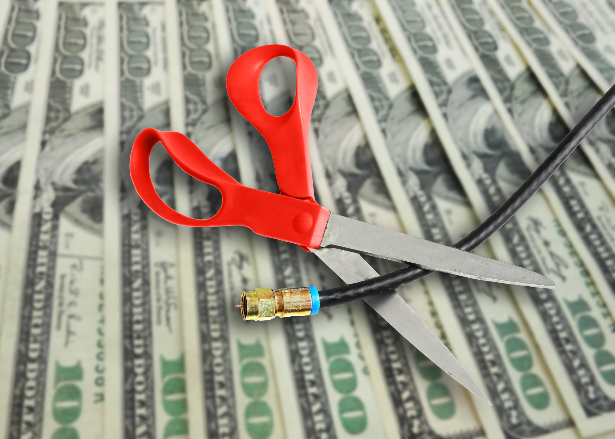 Scissors cutting cable over $100 bills