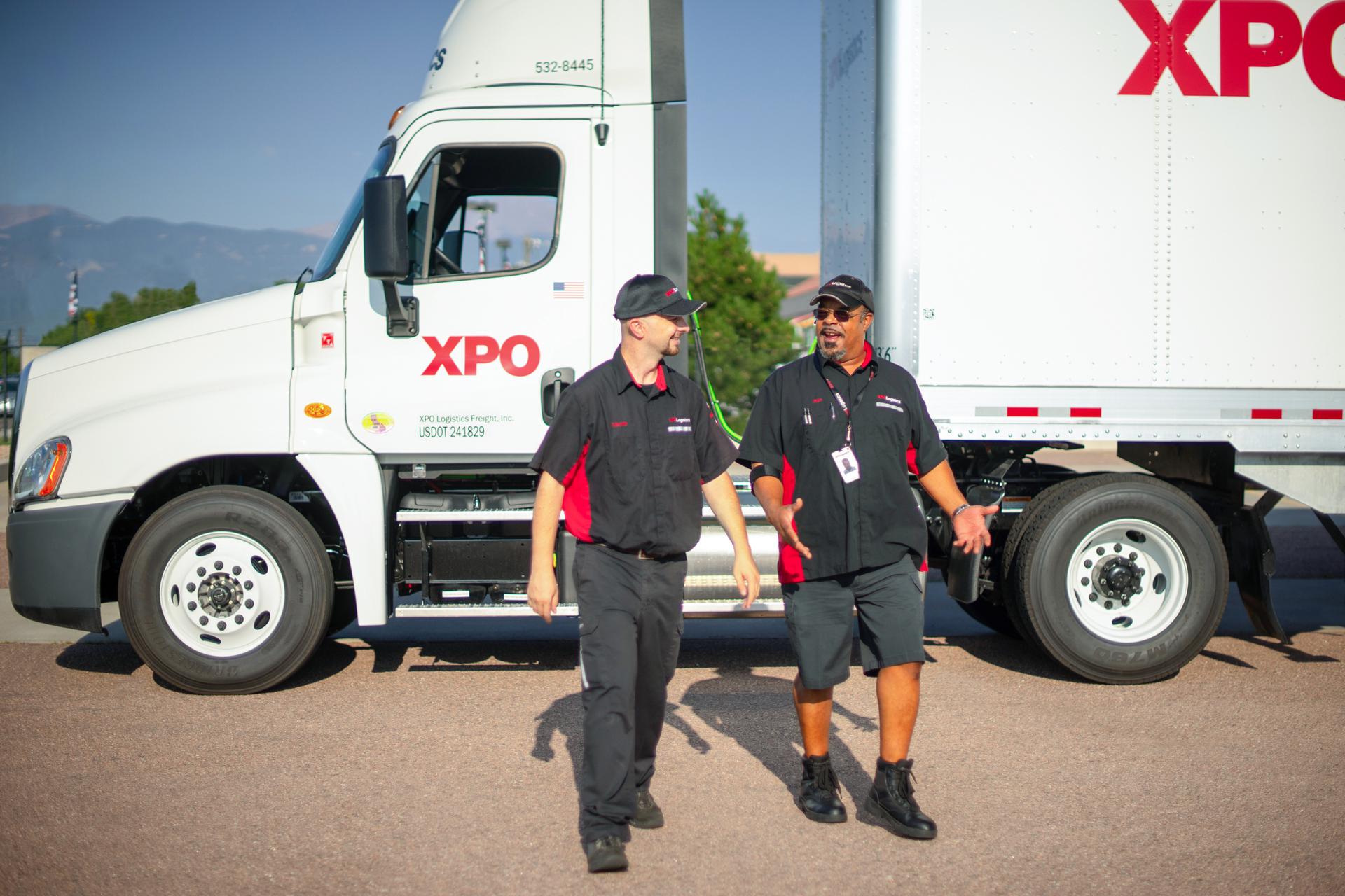 Two XPO Logistics drivers with a company truck in the background.