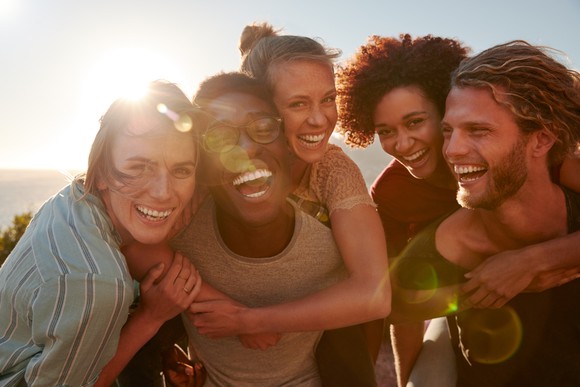 A group of smiling young adults taking a photo outdoors.