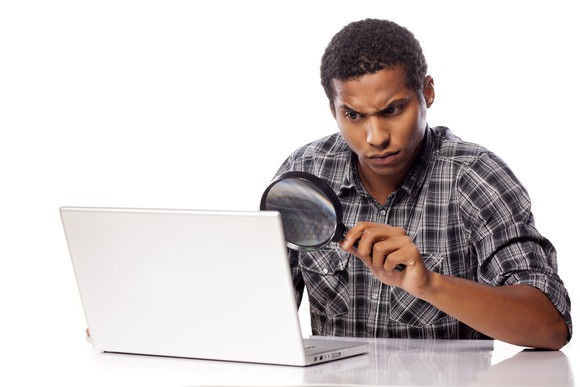 Man looking through magnifying glass at his computer screen