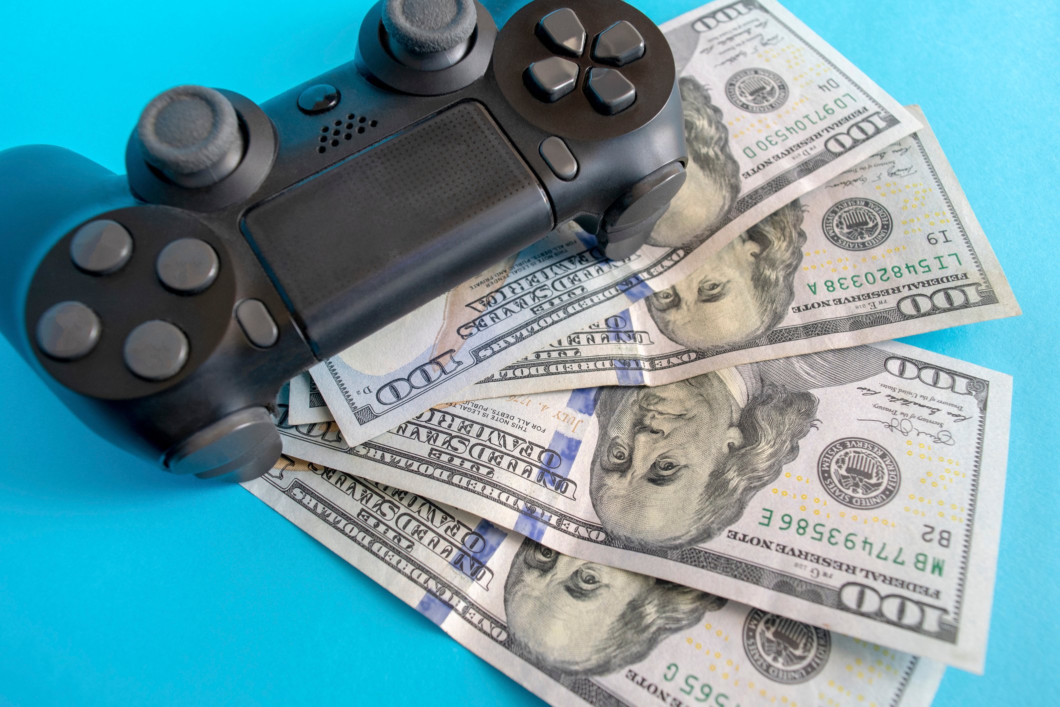 A video game controller on top of four hundred-dollar bills.
