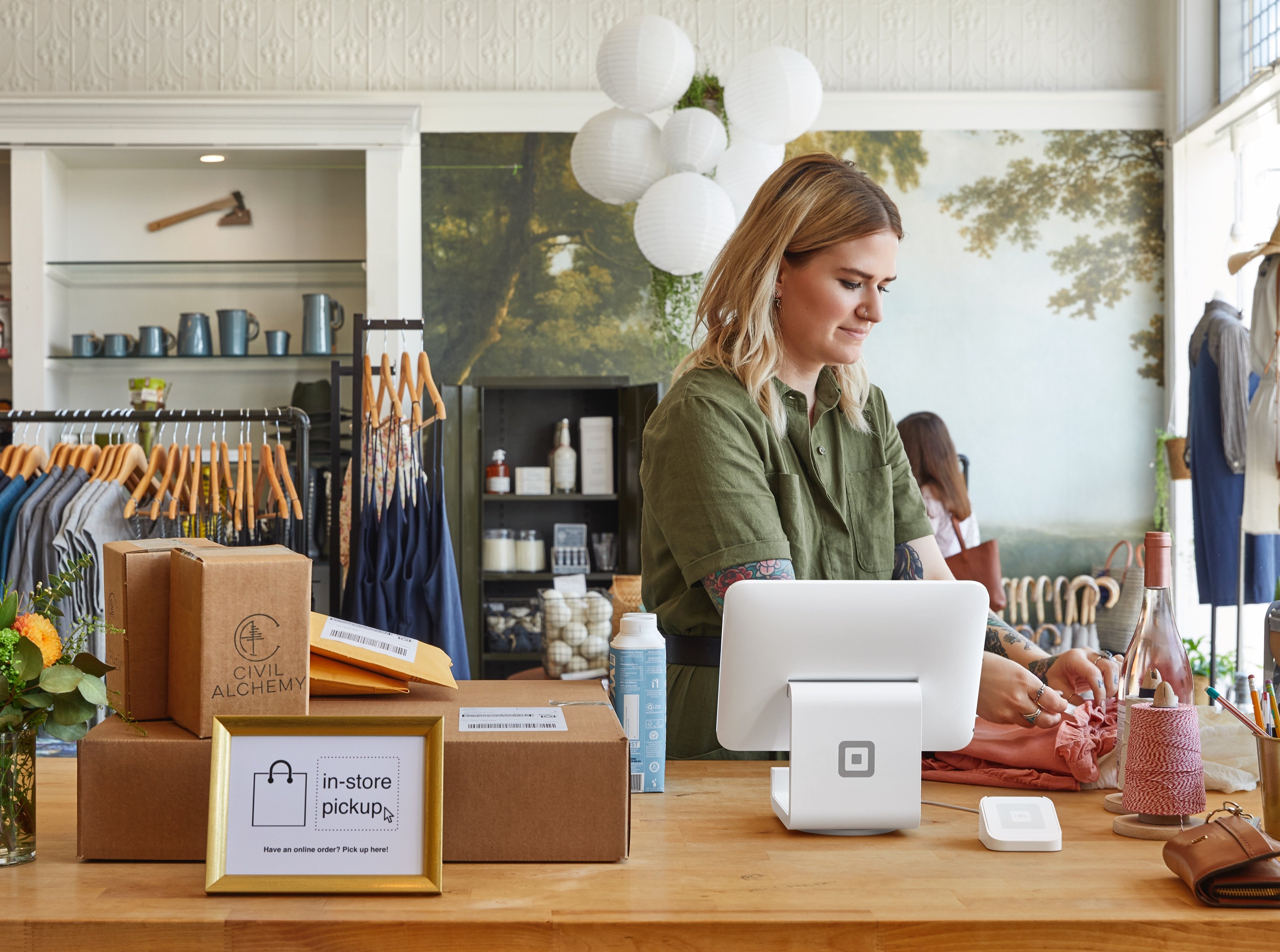 A merchant prepares an order with a square terminal on the counter.