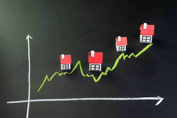 graph on chalkboard with uptrend showing houses along the way