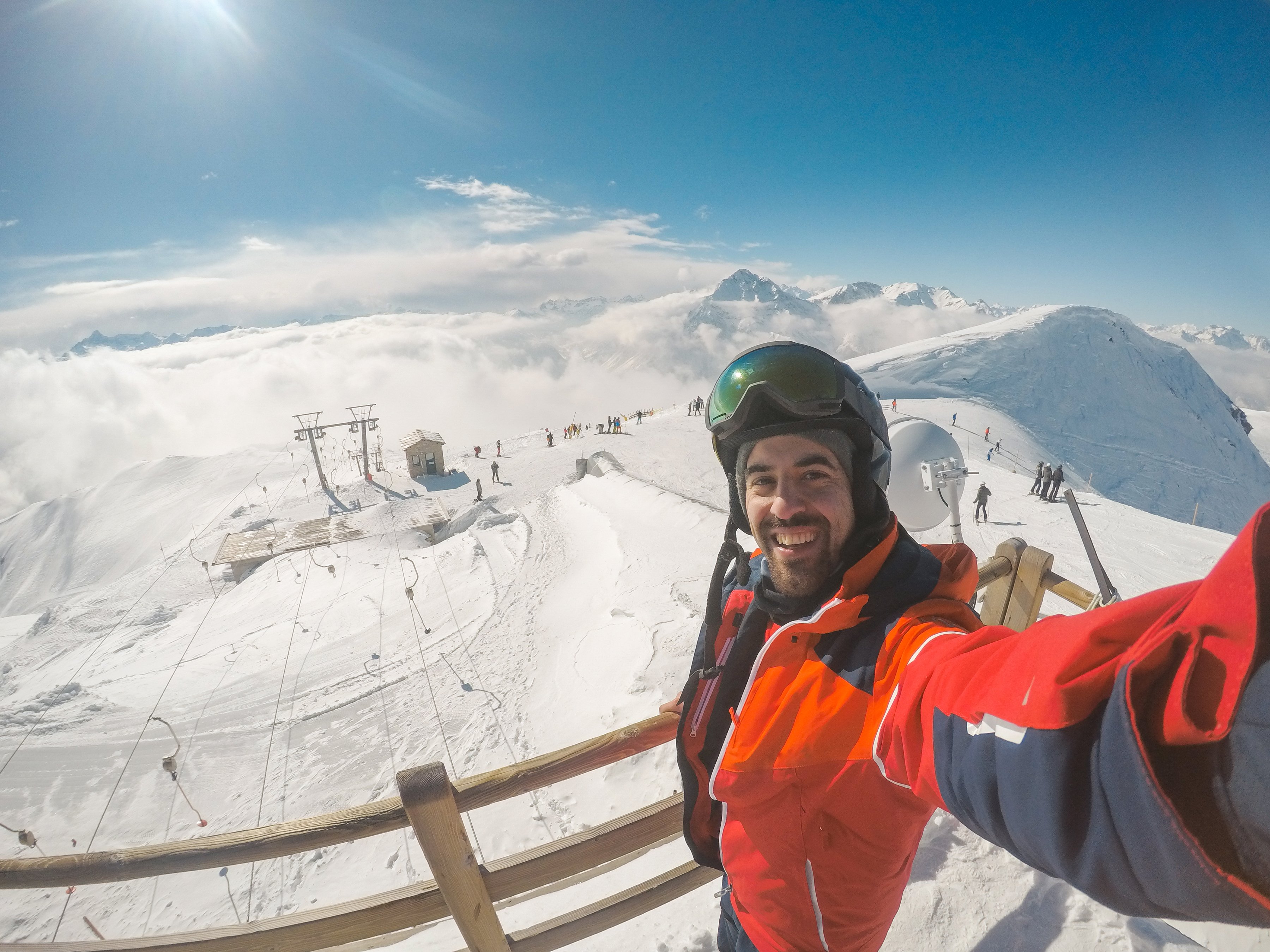 skier holding action camera with slope activity behind him