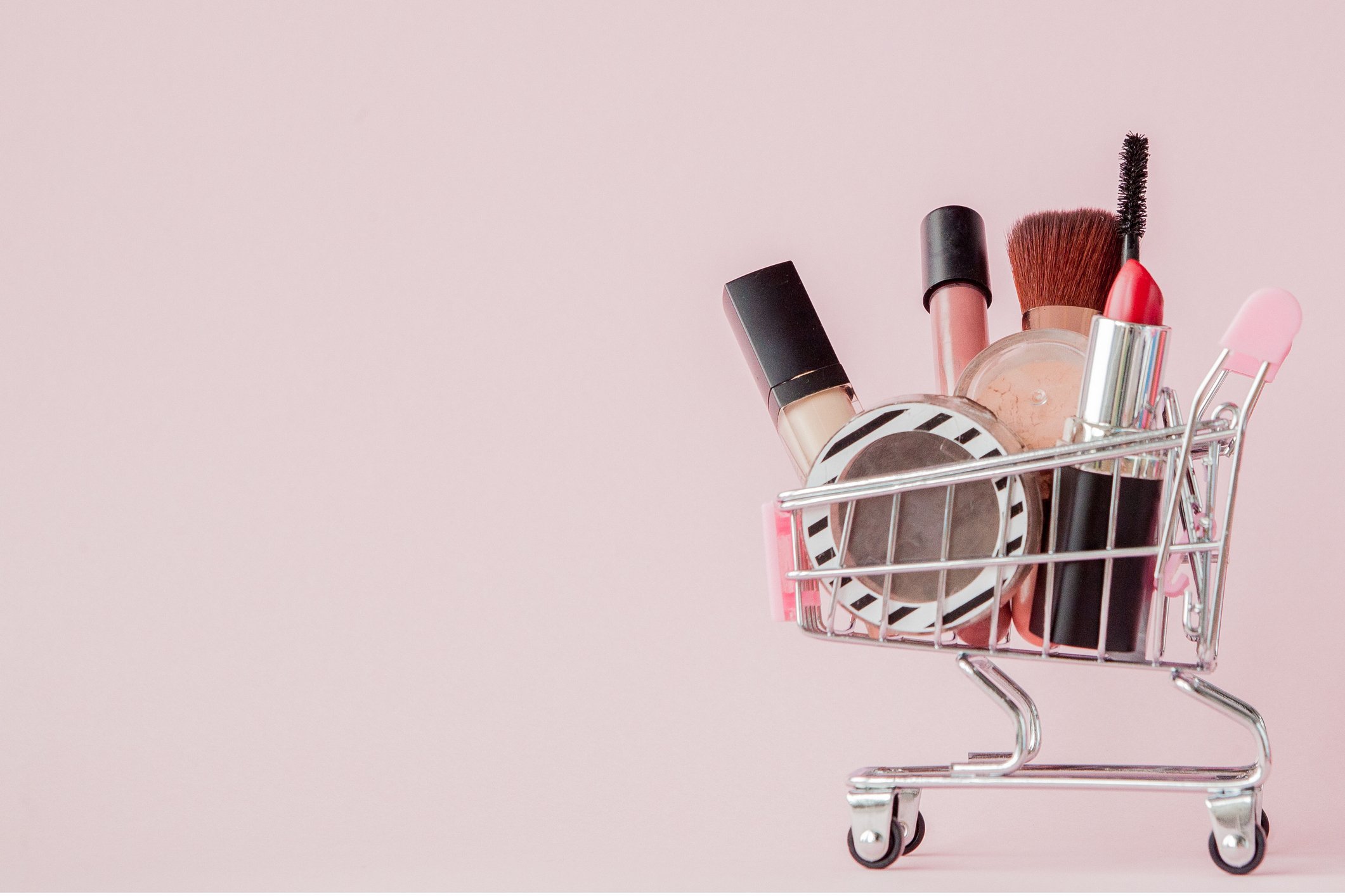 A miniature shopping cart filled with cosmetics.