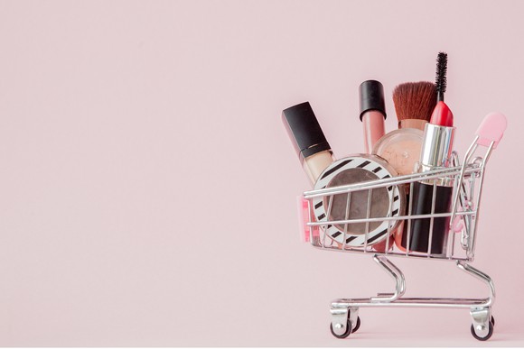 A miniature shopping cart filled with cosmetics.