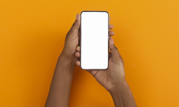 Two hands hold a smartphone with a blank screen. 