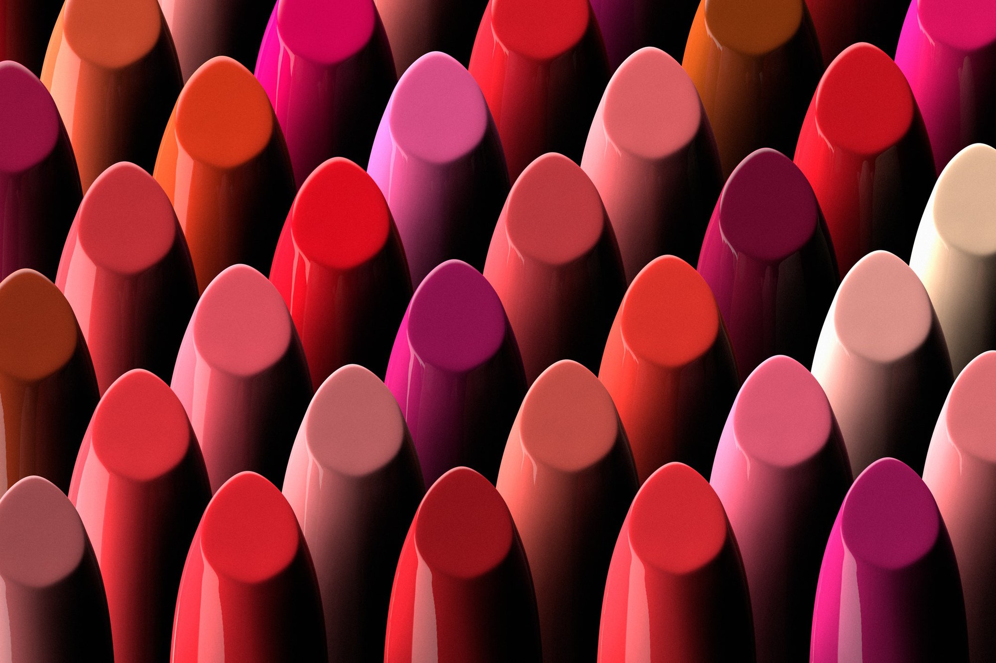 Numerous shades of lipstick are lined up in rows.