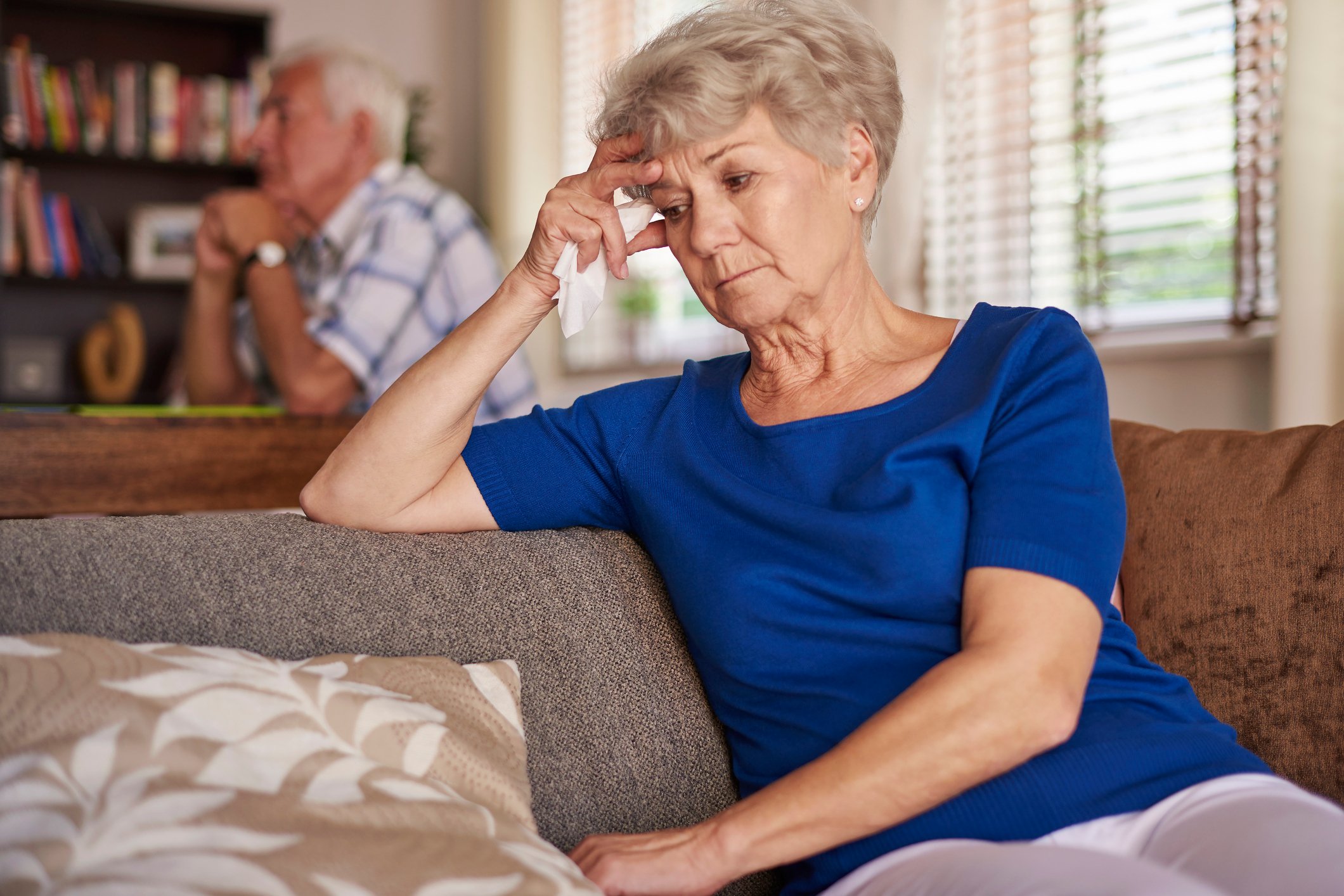 Senior man and woman sitting in the house looking worried