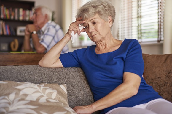 Senior man and woman sitting in the house looking worried