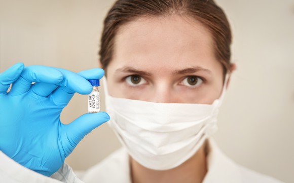 A researcher holds up a dose of coronavirus vaccine.