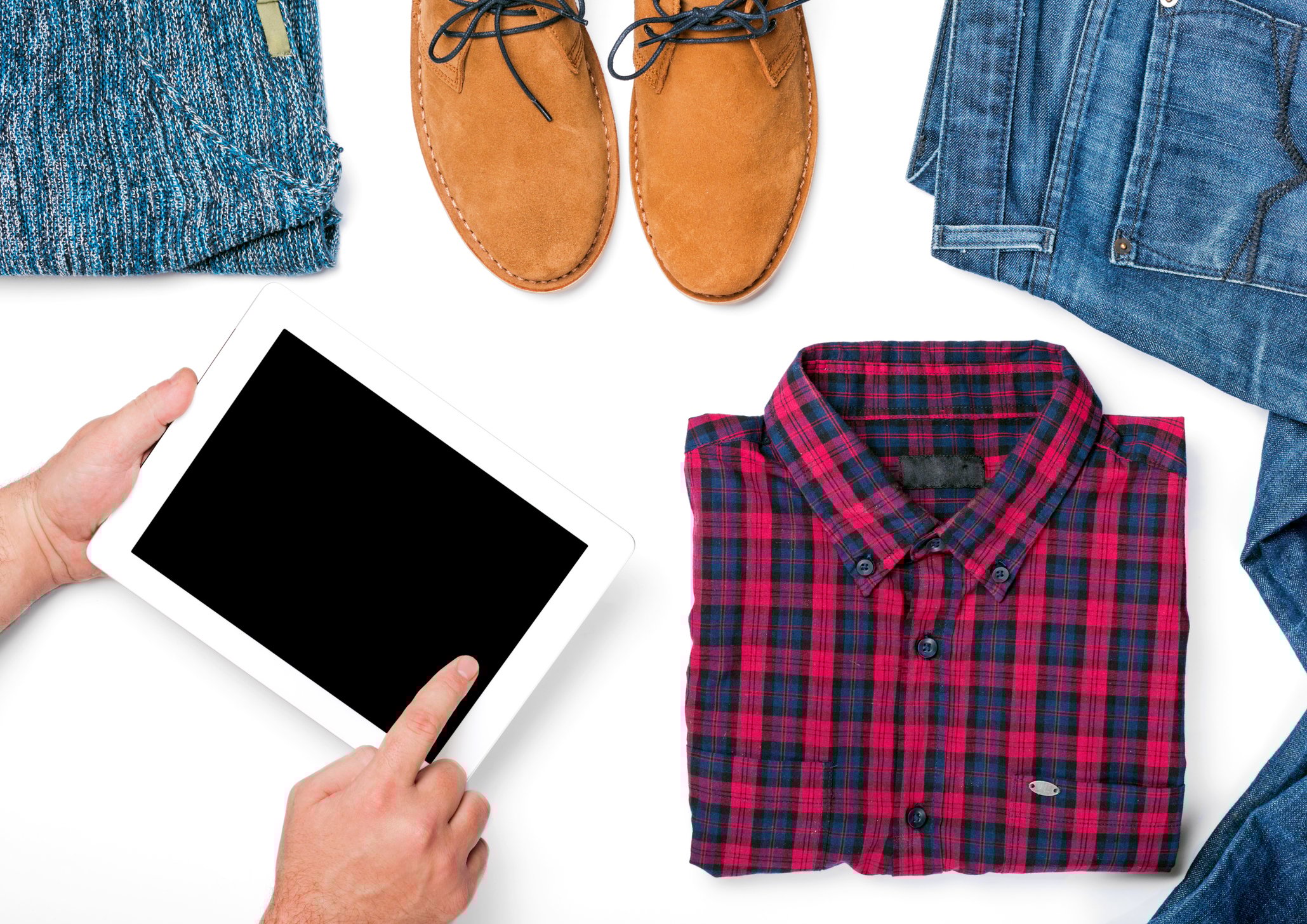 Customer using tablet with a new shirt, jeans, and a pair of shoes laid out on a tabletop.