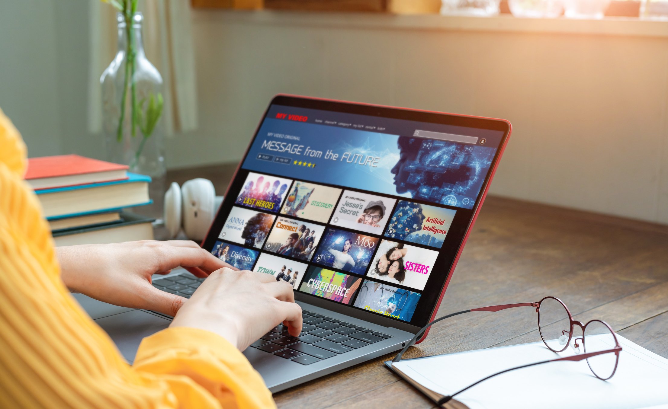 Picture of a person typing on a laptop, watching a streaming video service.