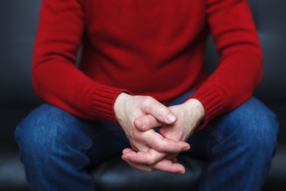 A man sitting with his fingers crossed. 