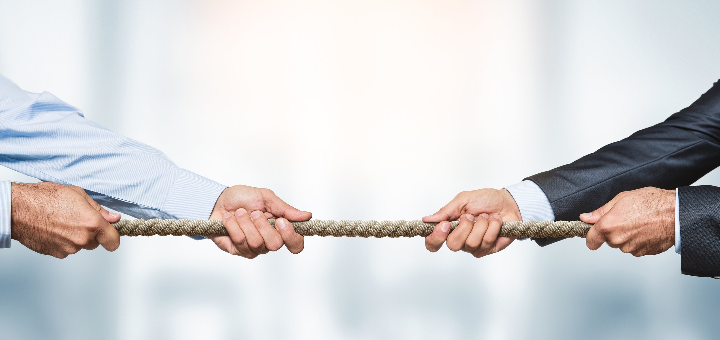 Two businessmen engage in an act of tug of war with a rope.