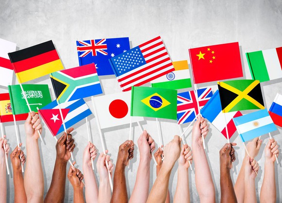 A dozen hands holding flags of various countries.