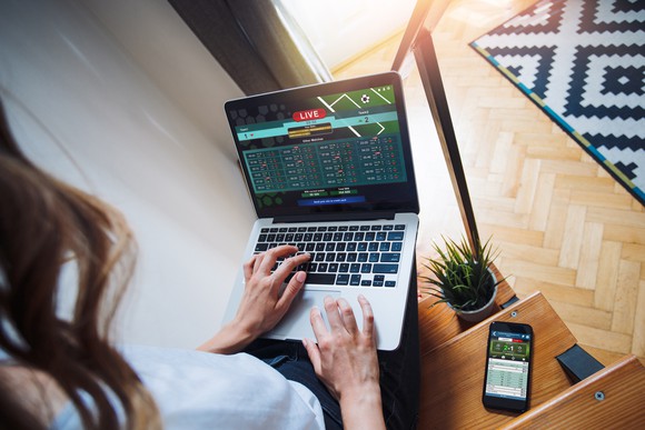 woman sports betting online with laptop and smartphone