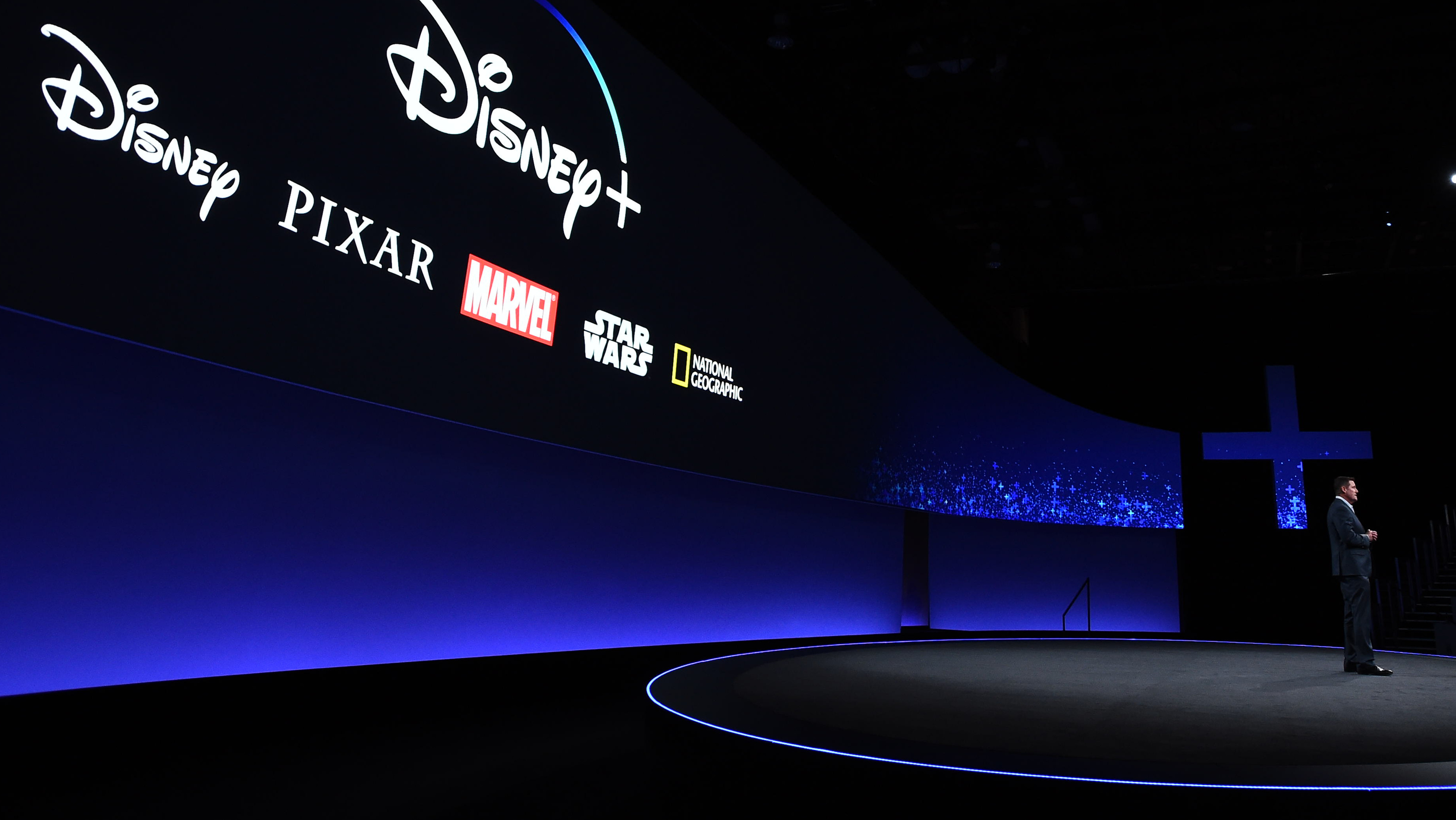 A large screen showing the logos for Disney+ and other content brands during a company presentation.