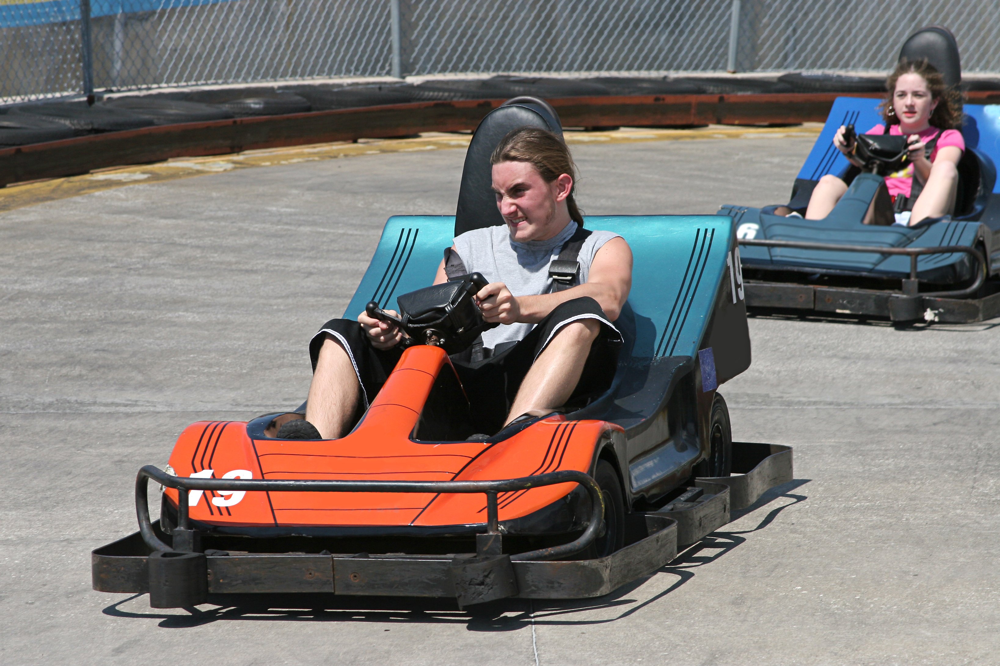 Two electric bumper cars race around a track.