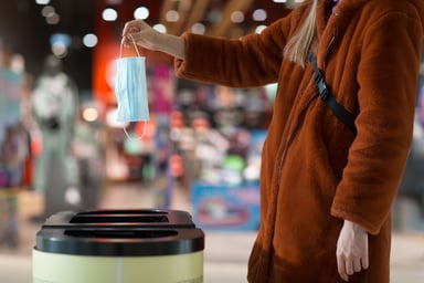 Woman holding a mask over a trash can