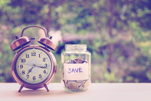 Alarm clock next to a savings jar.