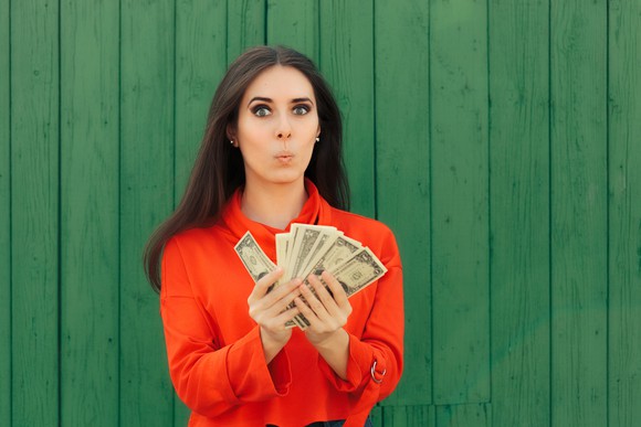 A woman holding a stack of dollar bills.