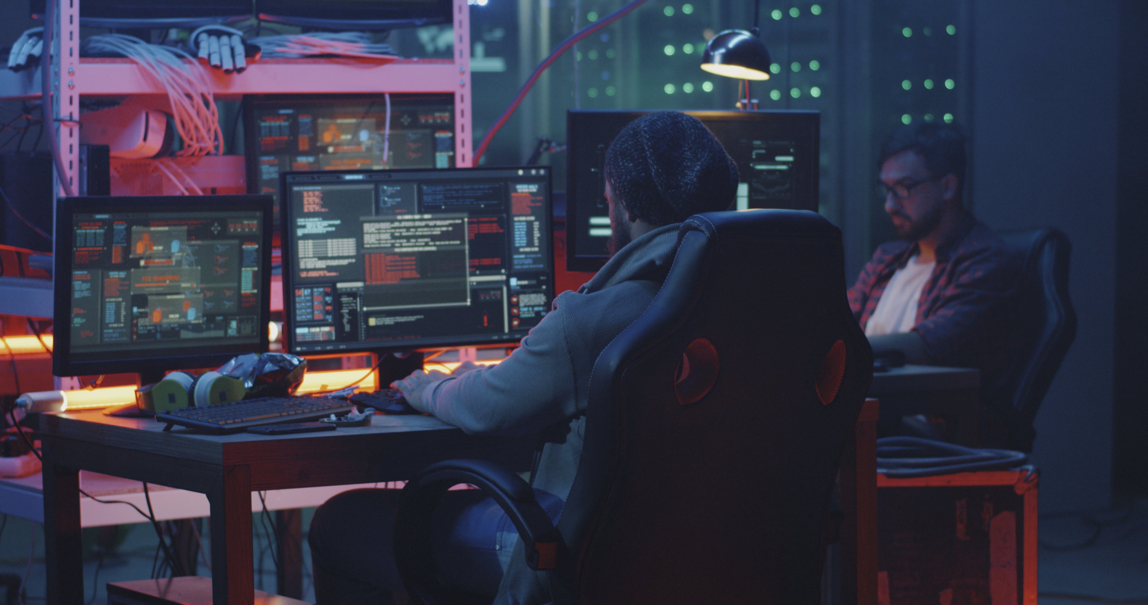 Two hackers seated at a desk and working.