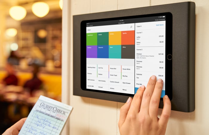 A restaurant worker using Square's services on a wall-mounted terminal.