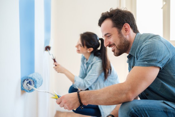 A man and woman paint a room together.