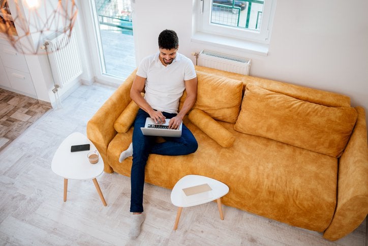 Aeriel view of a man using a laptop while sitting on his couch.