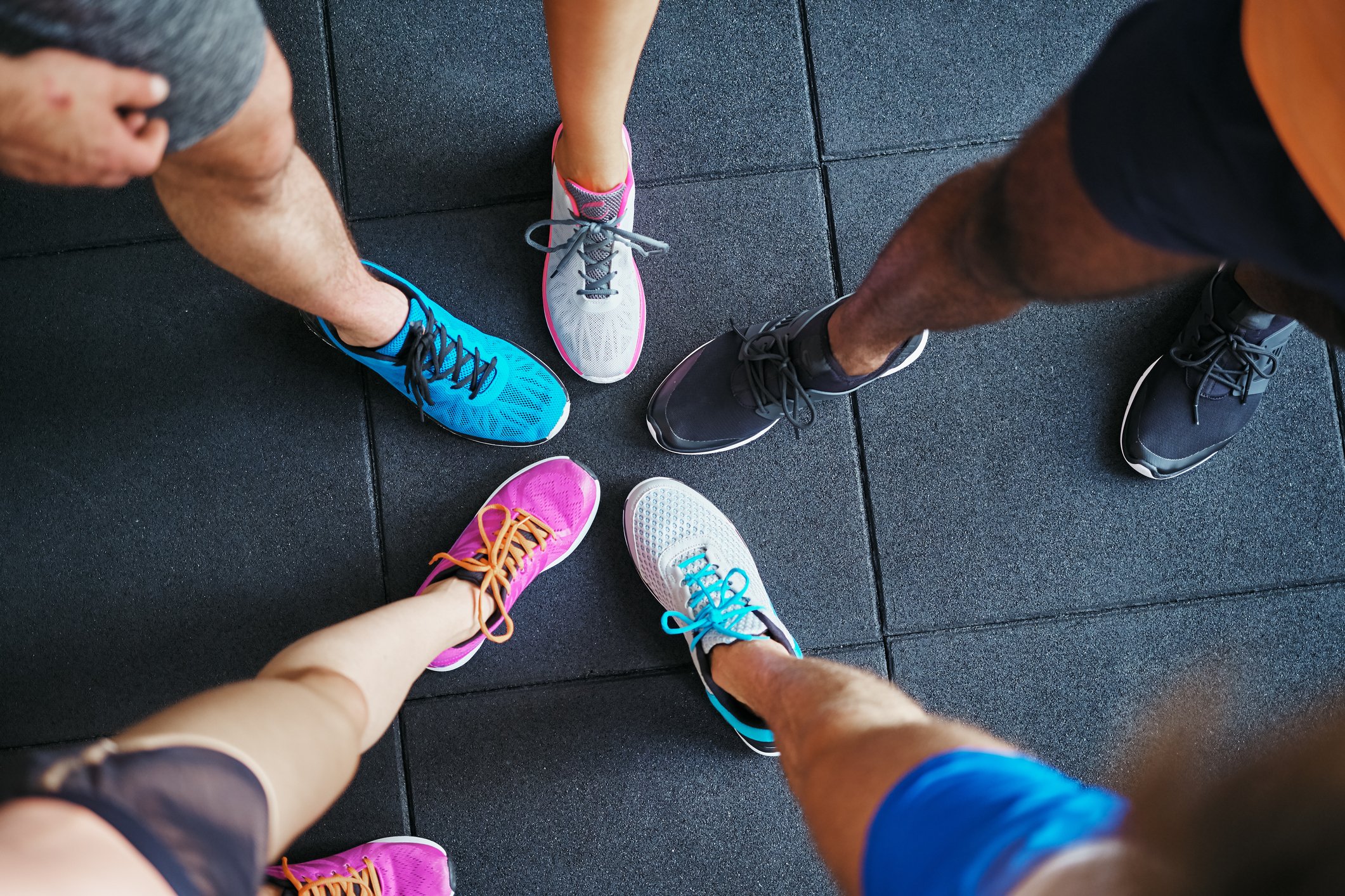 Picture of five people standing together wearing different athletic shoes.