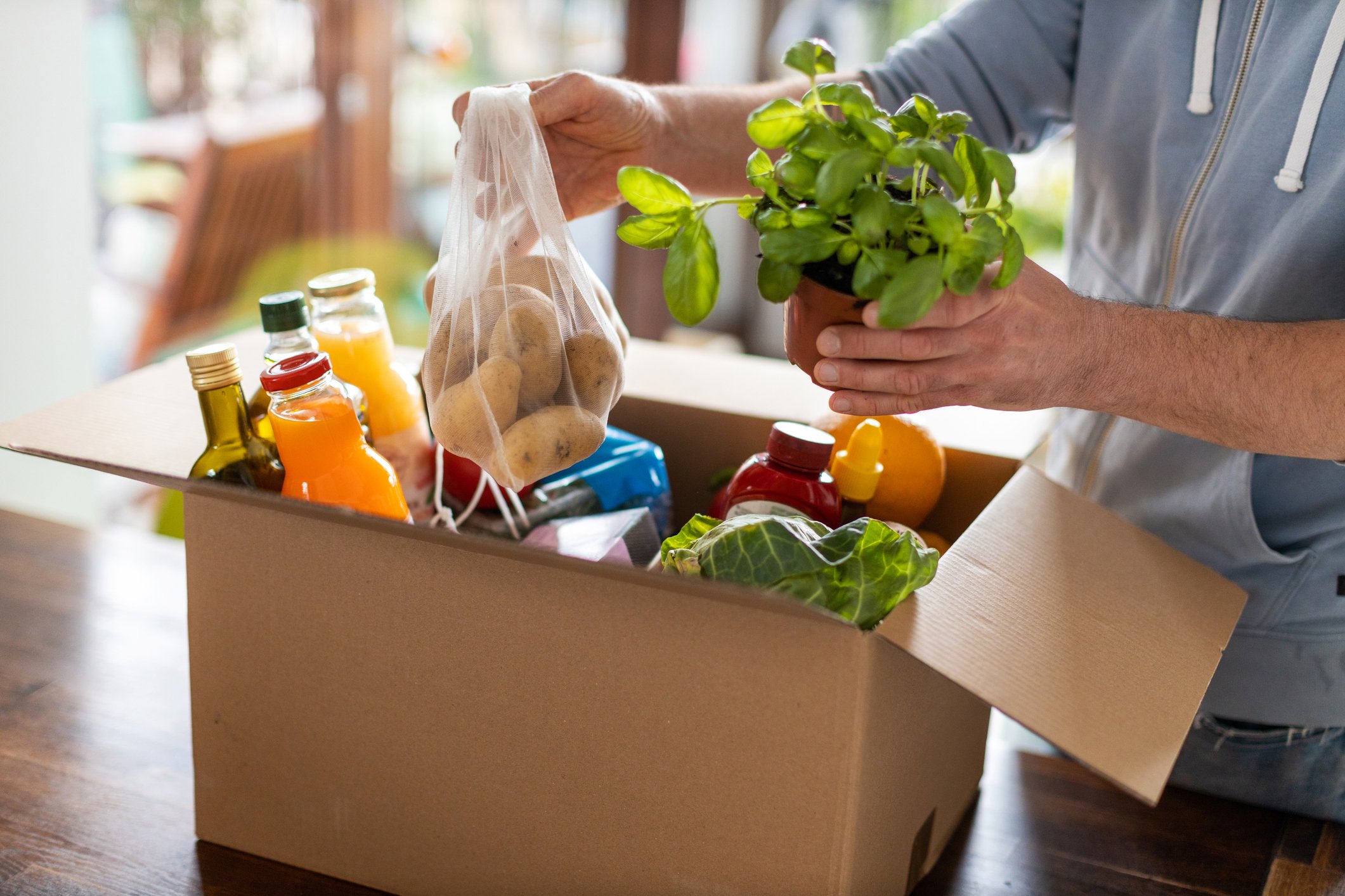 A man opens a box of delivered groceries.