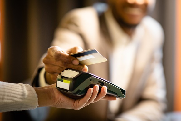 Man holding credit card above card terminal to make a payment